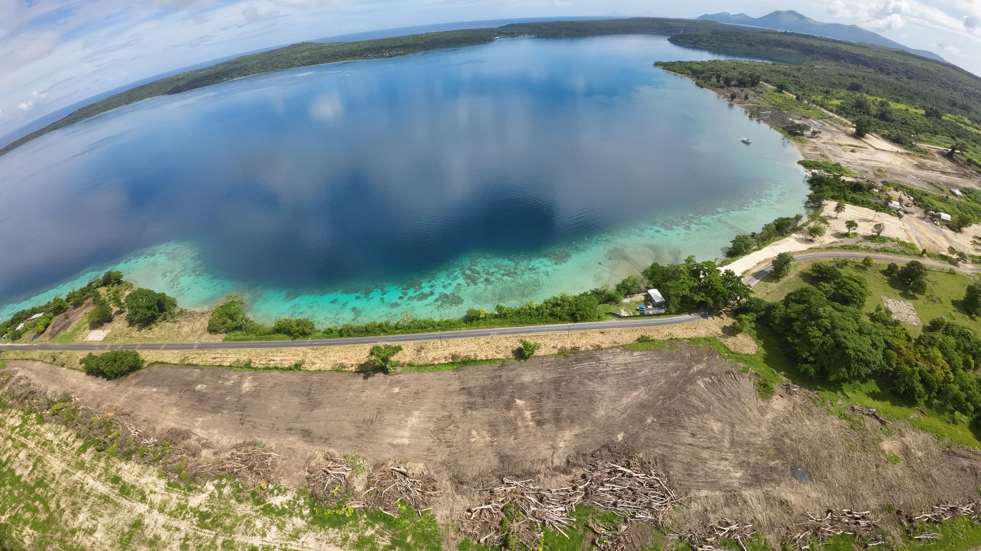 Vue aérienne sur Havannah Harbour. La Ring Road d'Efate longe le rivage ; au premier plan, le terrain fraîchement dégagé des lots commerciaux entre la route et la piste, et le site de la marina tout à droite.